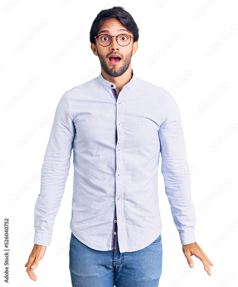 Fototapeta premium Handsome hispanic man wearing business shirt and glasses afraid and shocked with surprise and amazed expression, fear and excited face.