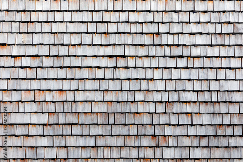 Traditional house wall cladding from weathered cut rectangular wooden shingles photo