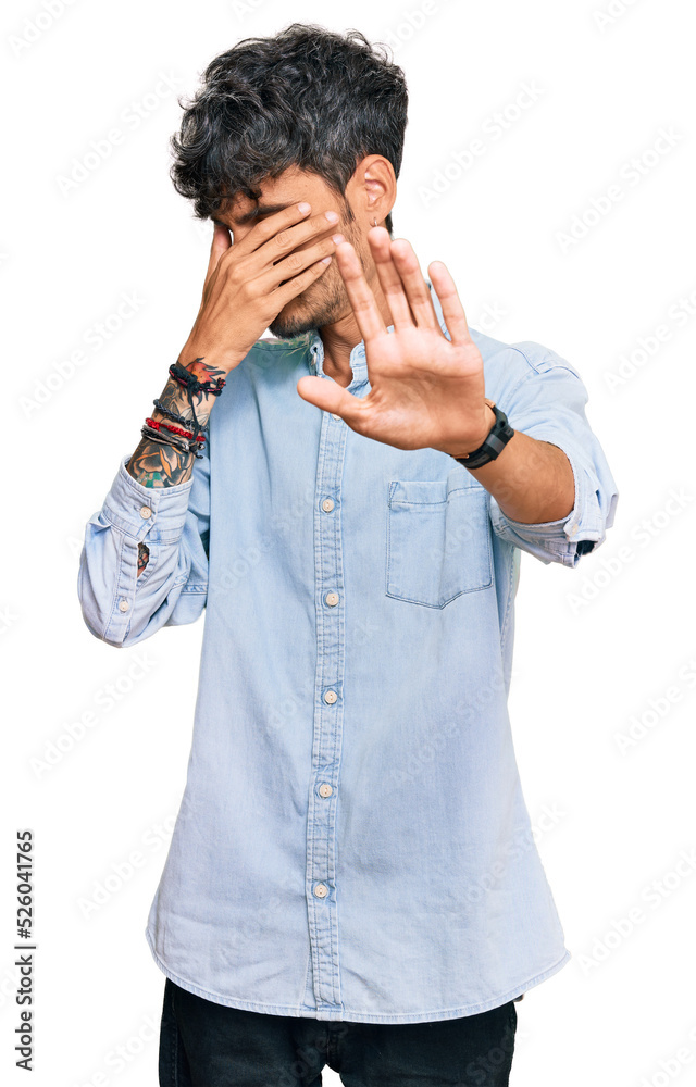 Young hispanic man wearing casual clothes covering eyes with hands and doing stop gesture with sad and fear expression. embarrassed and negative concept. Young hispanic man wearing casual clothes covering eyes with hands and doing stop gesture with sad and fear expression. embarrassed and negative concept.