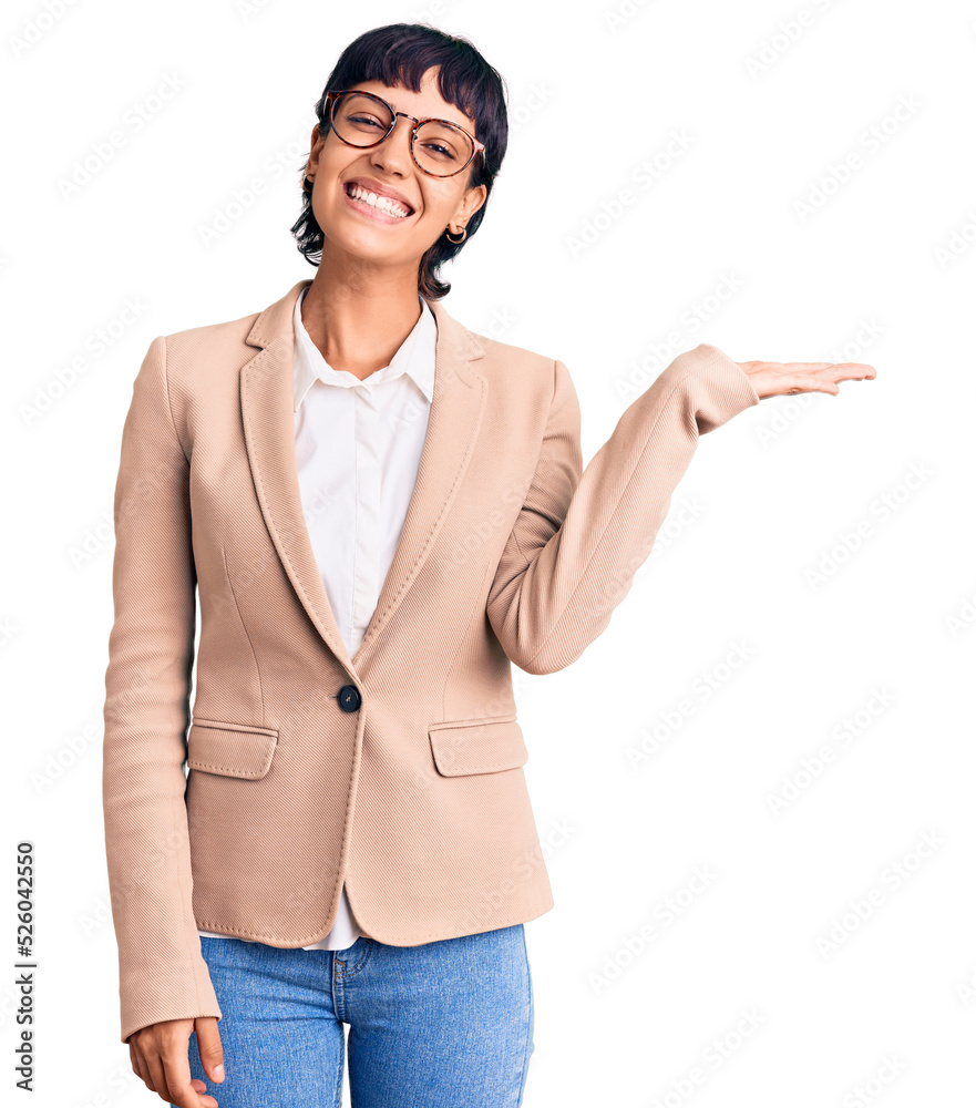 Young brunette woman with short hair wearing business jacket and glasses smiling cheerful presenting and pointing with palm of hand looking at the camera. Young brunette woman with short hair wearing business jacket and glasses smiling cheerful presenting and pointing with palm of hand looking at the camera.