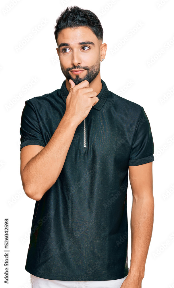 Young man with beard wearing sportswear with hand on chin thinking about question, pensive expression. smiling with thoughtful face. doubt concept.
