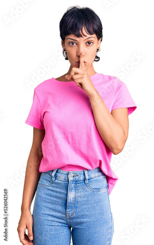 Young brunette woman with short hair wearing casual clothes asking to be quiet with finger on lips. silence and secret concept.