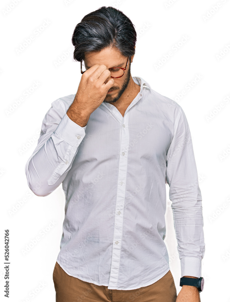 Young hispanic man wearing business shirt and glasses tired rubbing nose and eyes feeling fatigue and headache. stress and frustration concept. Young hispanic man wearing business shirt and glasses tired rubbing nose and eyes feeling fatigue and headache. stress and frustration concept.