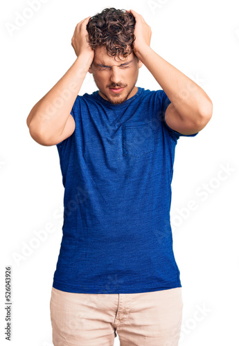 Young handsome man with curly hair wearing casual clothes suffering from headache desperate and stressed because pain and migraine. hands on head.