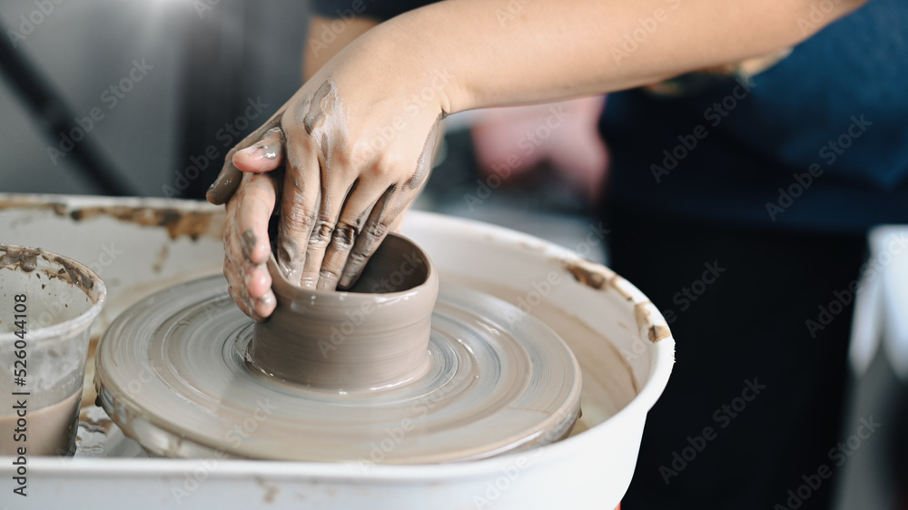 Close up view of female potter sculpting clay dishes on the pottery wheel in creative studio workshop. Activity, handicraft, hobbies concept Close up view of female potter sculpting clay dishes on the pottery wheel in creative studio workshop. Activity, handicraft, hobbies concept