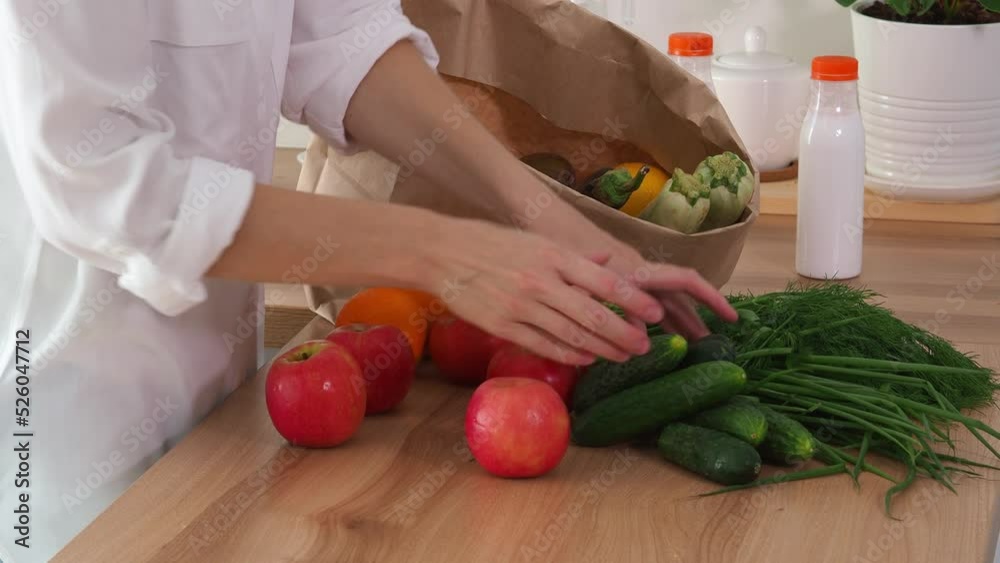 A woman puts organic farm vegetables and dairy products into a paper bag. Collect food in an eco bag and take it away. Take the eco food package from the table. Conscious nutrition. Health care. A woman puts organic farm vegetables and dairy products into a paper bag. Collect food in an eco bag and take it away. Take the eco food package from the table. Conscious nutrition. Health care.