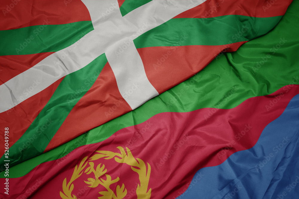 waving colorful flag of eritrea and national flag of basque country.