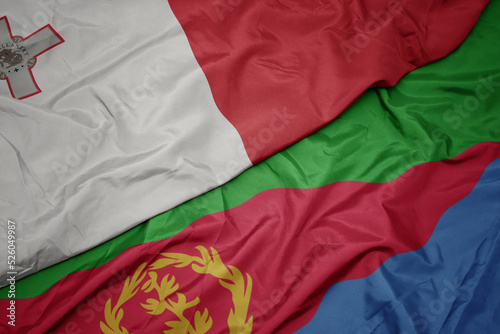 waving colorful flag of eritrea and national flag of malta.