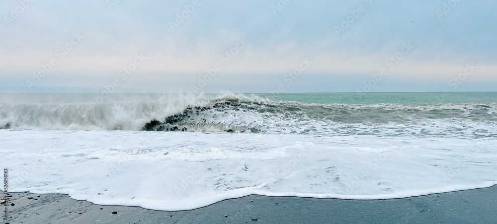 Panoramic seascape. Beautiful wave of the sea on the black sandy beach