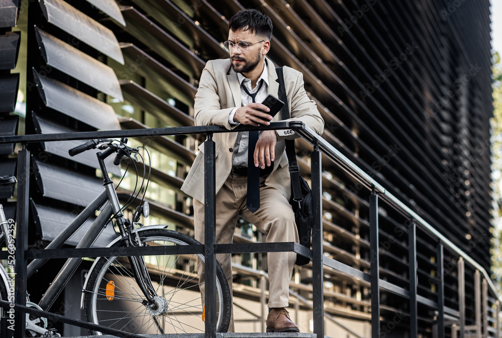 Portrait of business man with bicycle standing in front of office building. Portrait of business man with bicycle standing in front of office building.