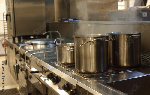 saucepans of boiling soup on oven in a restaurant kitchen