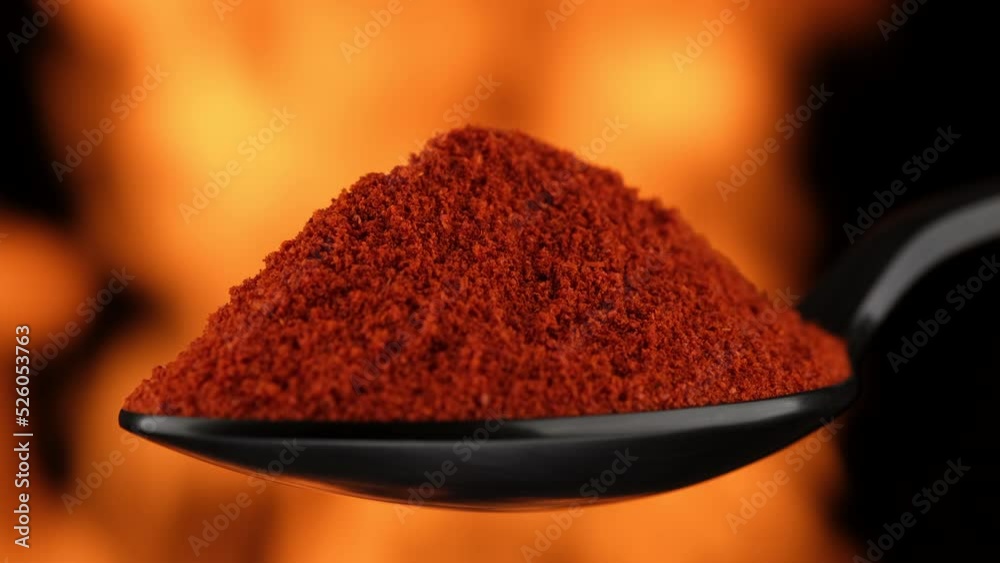 Smoked paprika spice in spoon, over open fire