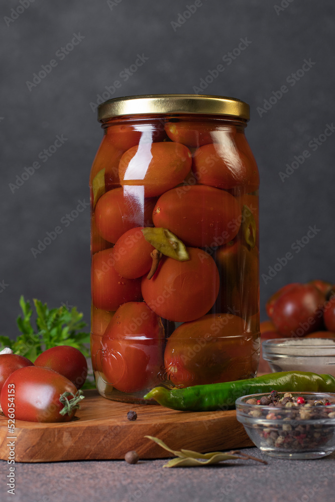 Homemade pickled tomatoes with chili peppers and parsley in jar on dark gray background, front view Homemade pickled tomatoes with chili peppers and parsley in jar on dark gray background, front view