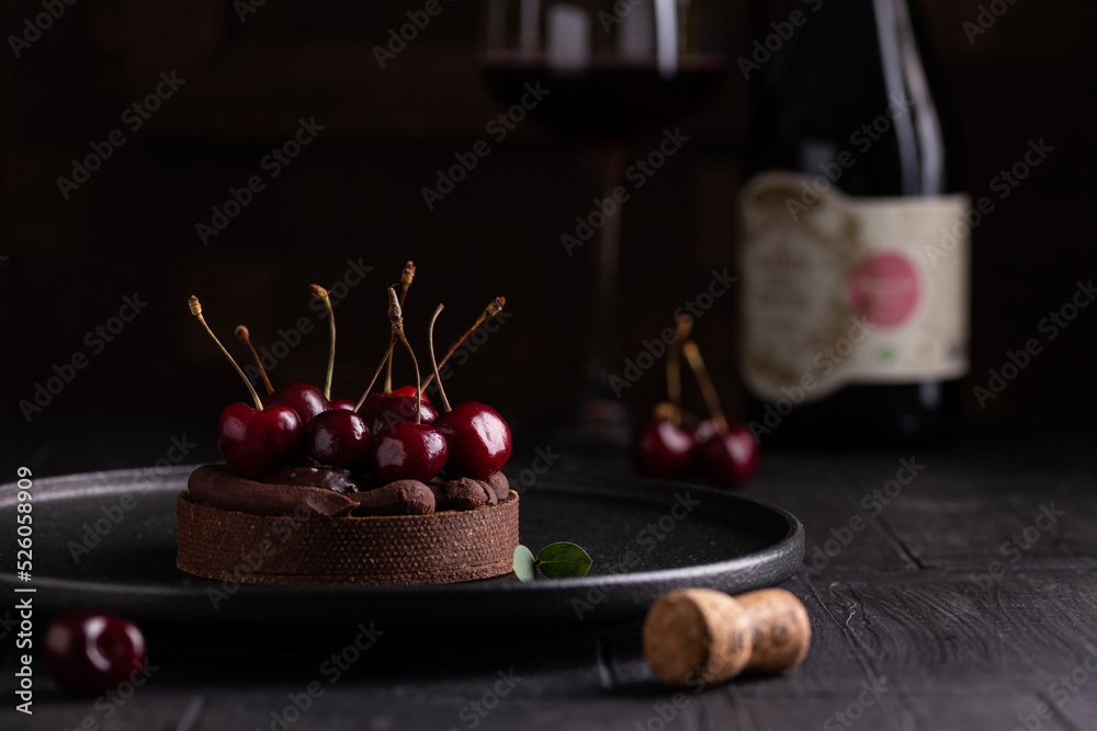 Cake with cherry and chocolate cream on a black plate