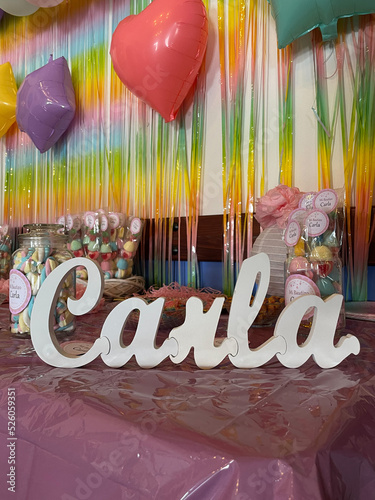 Colorful balloons, streamers, party props and knick-knacks on a pink table with Carla's name on it