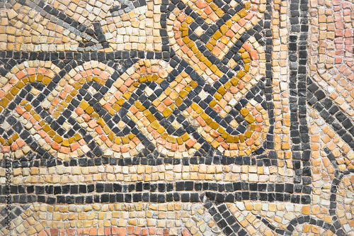 Ancient Italian Roman mosaic floor with circular shapes composed of small colored stone tiles - corner concept