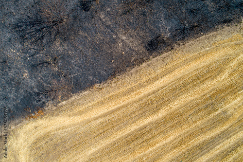 aerial view of scrubland burnt by fire next to a field of mown wheat Fototapeta