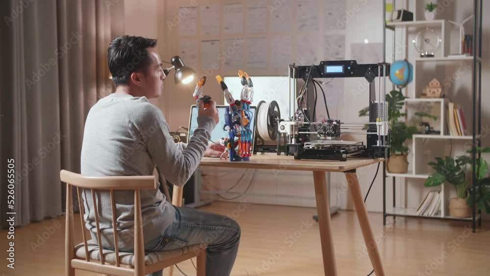 Back View Of Asian Male With 3D Printing Assembling A Cyborg Hand While Designing It On A Laptop At Home
Back View Of Asian Male With 3D Printing Assembling A Cyborg Hand While Designing It On A Laptop At Home