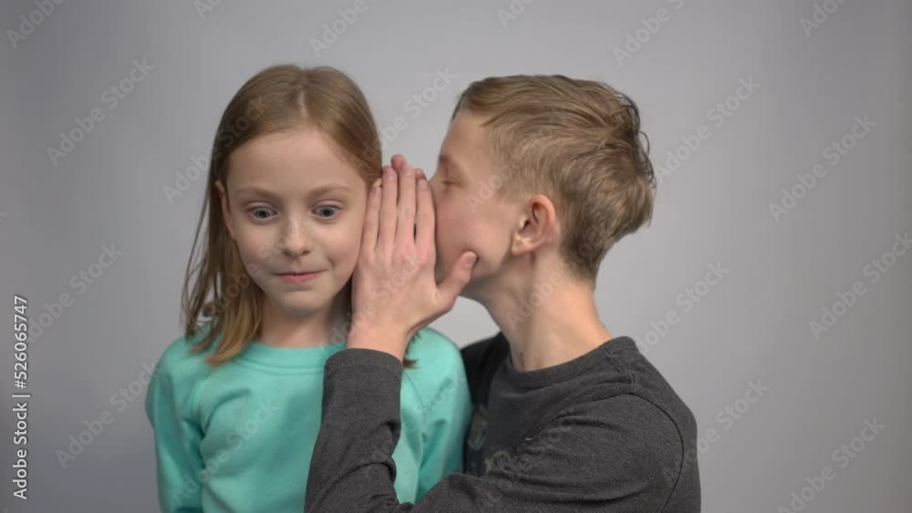 4k Little girl and boy are whispering in ear, isolated over gray 4k Little girl and boy are whispering in ear, isolated over gray