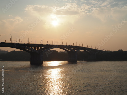 View from the high on Nizhny Novgorod city in Russia, Kanavinsky Bridge over the Oka River at sunset, moving cars on the bridge and on the road © Yulia