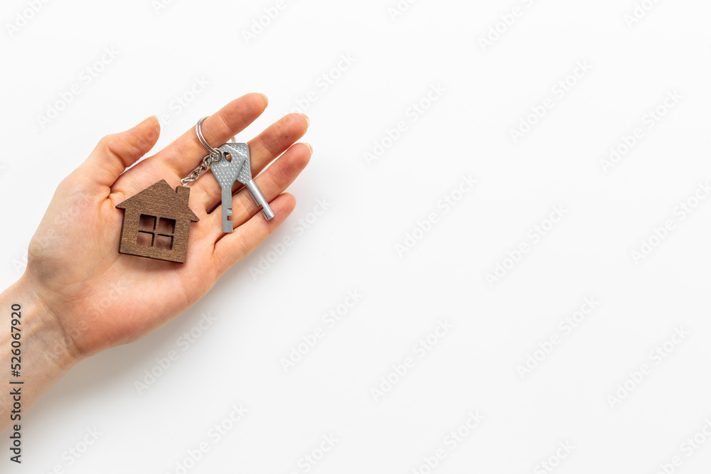 House shaped keychain and keys in hand. Sale or rent real estate concept House shaped keychain and keys in hand. Sale or rent real estate concept