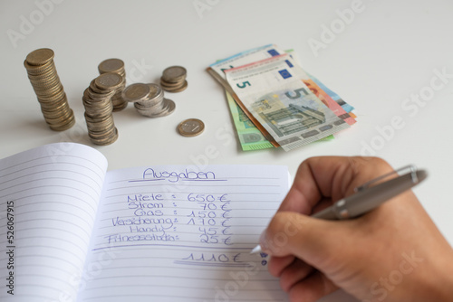 Mann schreibt seine Ausgaben auf eine liste und zählt sein Geld, während der Inflation