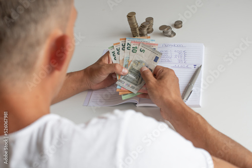 Mann schreibt seine Ausgaben auf eine liste und zählt sein Geld, während der Inflation