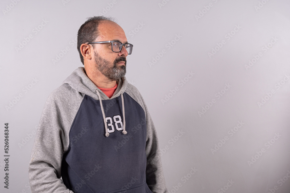Obraz premium Close-up man in his 60s wearing eyeglasses, against gray wall background with copy space