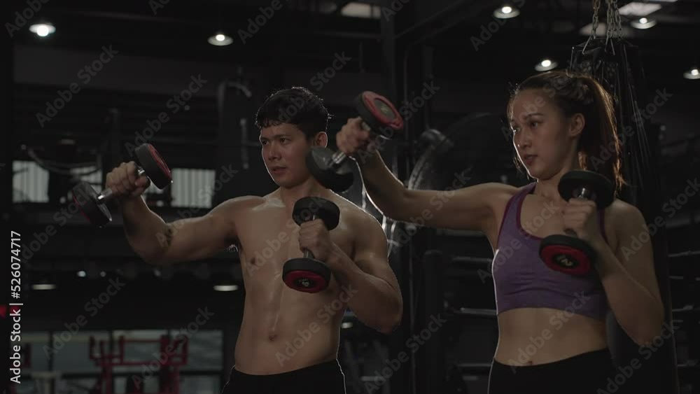 Asian  woman training with dumbbell exercise workout at fitness gym in sportswear with personal trainer.