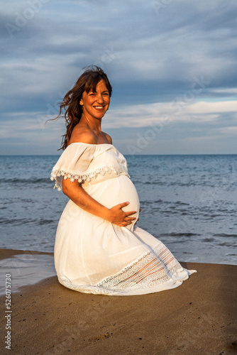 A young pregnant woman on a beach touching her pregnancy belly