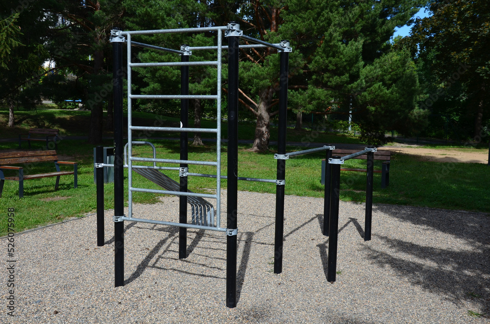fitness sports fields with stainless steel tools resemble torture tools with chains and handles. soft rubber surface sports ground outdoor gym. man holds a pulley and strengthens muscles