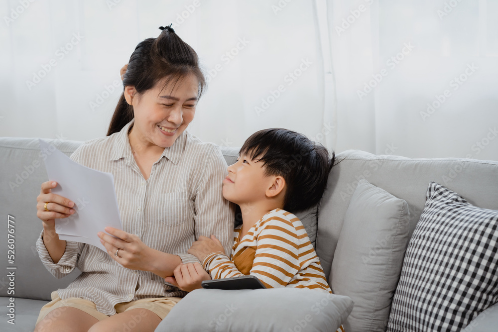 Asian boy, And his mother is working on a laptop computer, The little boy put the tablet in his hand and turned to his busy mother intently, wanting his mother to pay attention to him. Asian boy, And his mother is working on a laptop computer, The little boy put the tablet in his hand and turned to his busy mother intently, wanting his mother to pay attention to him.