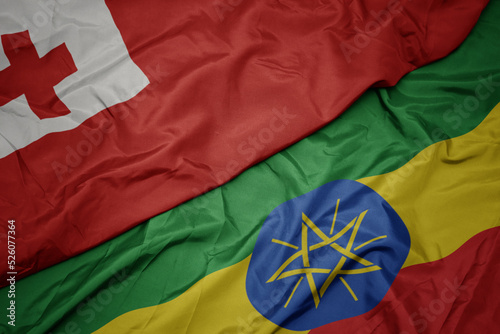 waving colorful flag of ethiopia and national flag of Tonga .