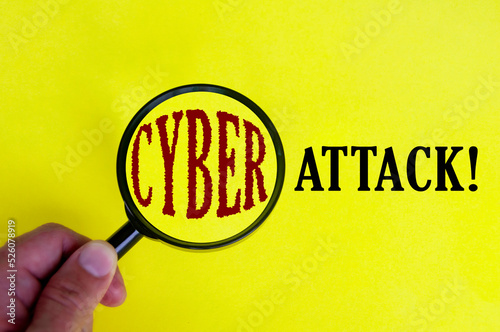 Cyber attack text on yellow cover with hand holding magnifying glass. Internet security concept