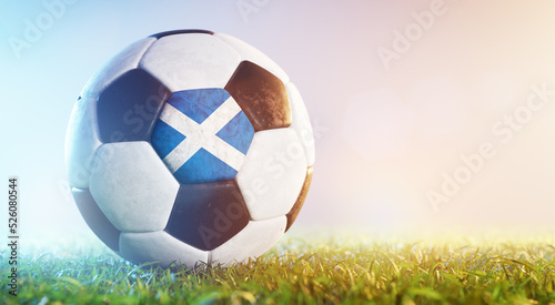 Football soccer ball with flag of Scotland on grass
