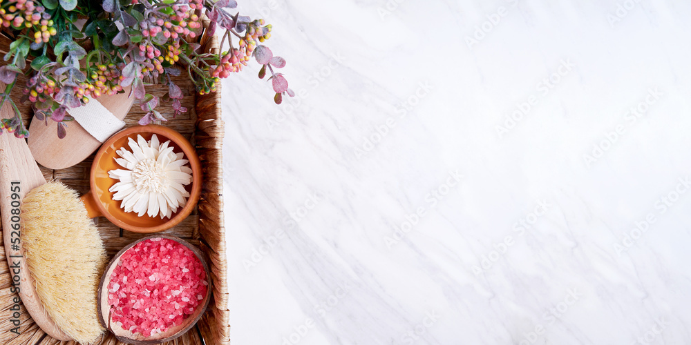 Basket with spa set with flowers, sea salt, herbs, plants on the marble floor. Template with copy space for text Basket with spa set with flowers, sea salt, herbs, plants on the marble floor. Template with copy space for text
