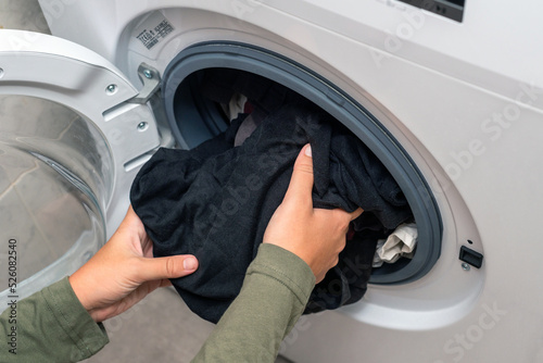 Young woman putting laundry in a washing machine