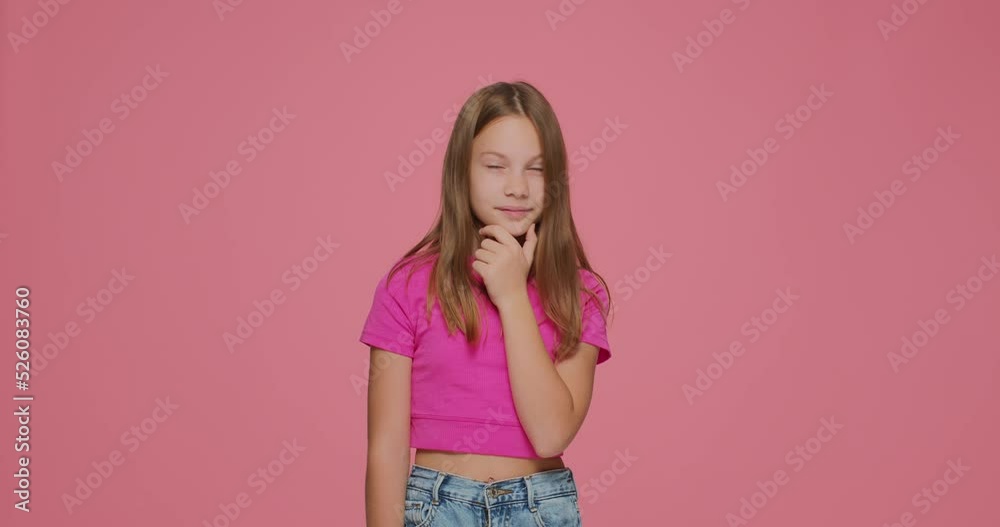 Pensive puzzled child girl thinking out idea, planning, rubbing her chin, smiling on pink studio background Pensive puzzled child girl thinking out idea, planning, rubbing her chin, smiling on pink studio background
