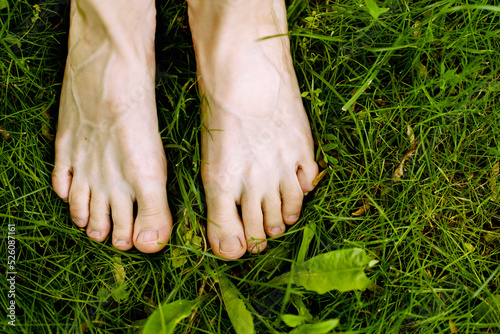 Bare woman's feet on the green grass. The concept of health and naturalness.