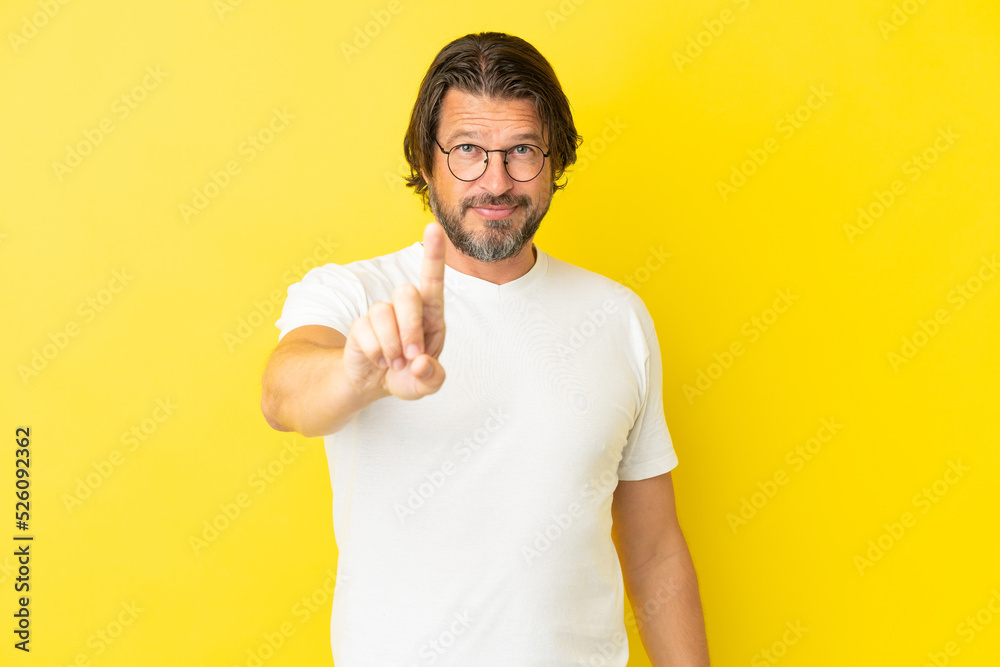 Senior dutch man isolated on yellow background showing and lifting a finger Senior dutch man isolated on yellow background showing and lifting a finger