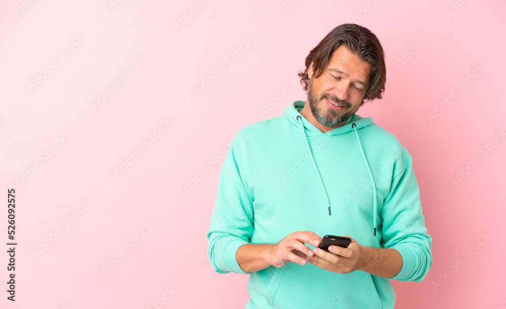 Senior dutch man isolated on pink background sending a message with the mobile Senior dutch man isolated on pink background sending a message with the mobile