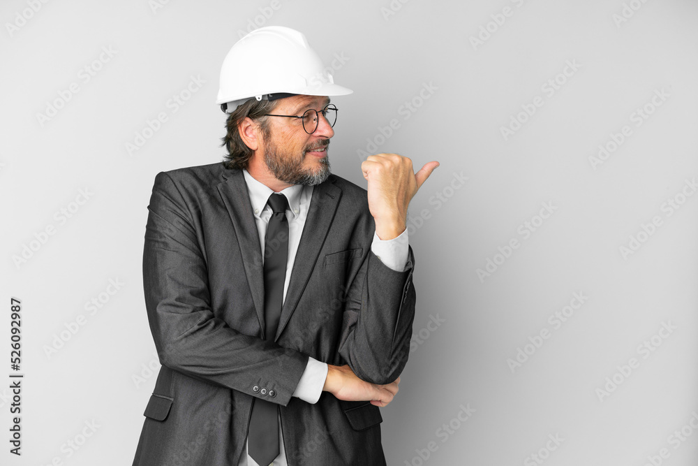 Young architect man with helmet over isolated background pointing to the side to present a product Young architect man with helmet over isolated background pointing to the side to present a product