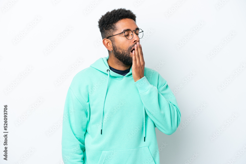 Young Brazilian man isolated on white background yawning and covering wide open mouth with hand Young Brazilian man isolated on white background yawning and covering wide open mouth with hand