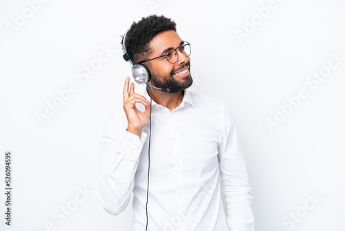 Telemarketer Brazilian man working with a headset isolated on white background thinking an idea