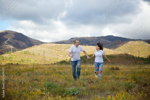 Happy couple in love running across the field.