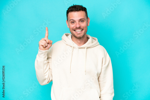 Young caucasian handsome man isolated on blue background pointing up a great idea