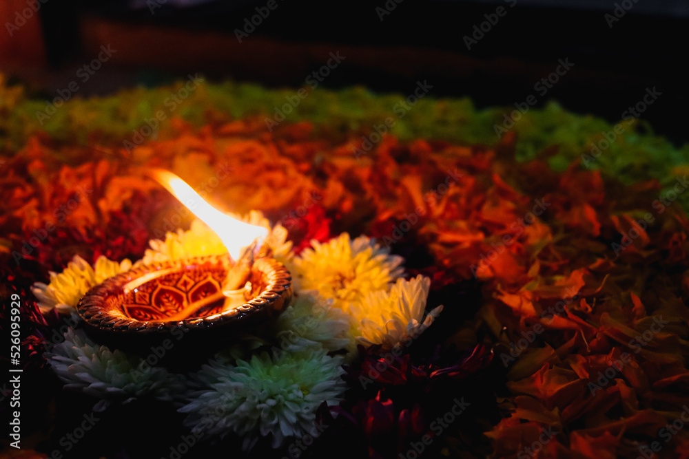 Lights of Lamp and Floral Decoration in Dark. Symbol of Indian Holiday Event. Oil Lamp and Petals Of Red and Yellow Flowers. Indian Culture Lights of Lamp and Floral Decoration in Dark. Symbol of Indian Holiday Event. Oil Lamp and Petals Of Red and Yellow Flowers. Indian Culture