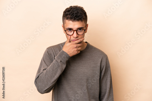 Young Brazilian man isolated on beige background thinking