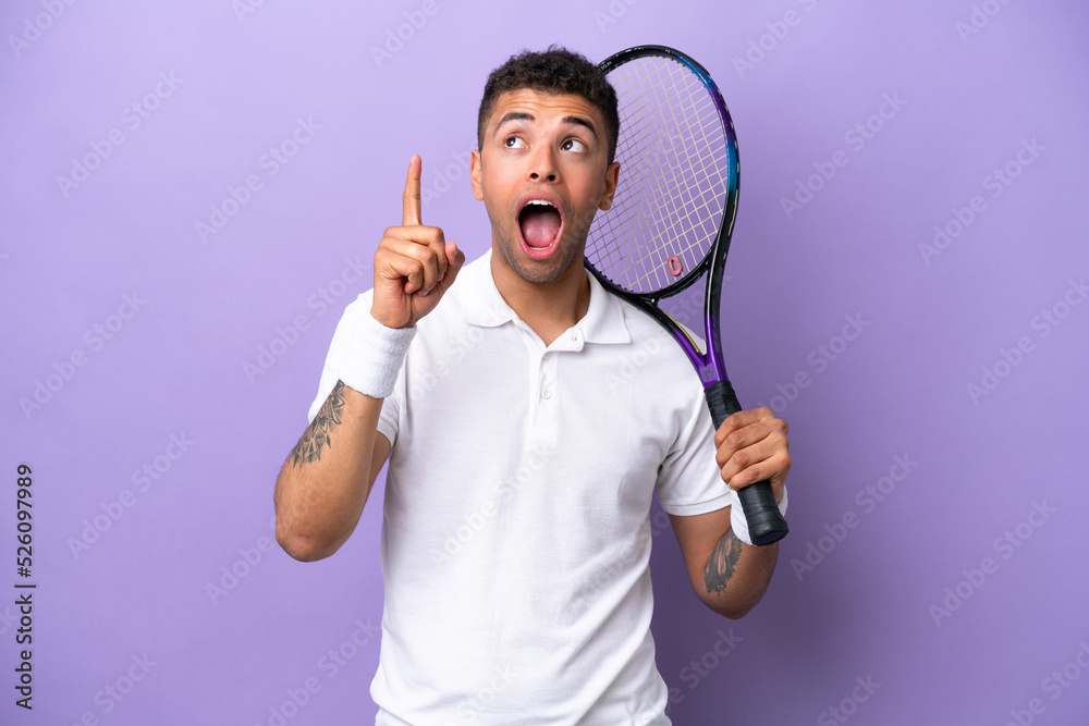 Young Brazilian man isolated on purple background playing tennis and pointing up Young Brazilian man isolated on purple background playing tennis and pointing up