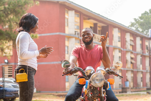 african lady describes her destination to a bike man